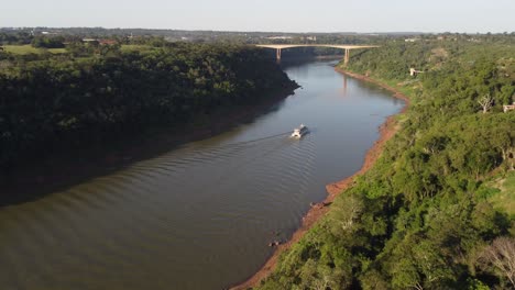 Luftaufnahme-Eines-Touristenbootes,-Das-Bei-Sonnenuntergang-Auf-Dem-Fluss-Iguazu-An-Der-Grenze-Zwischen-Argentinien-Und-Brasilien-Segelt