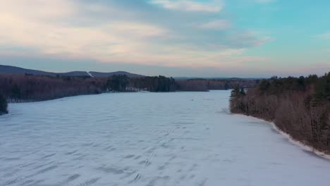 Volando-Sobre-Un-Lago-Congelado-En-Maine-Hacia-Dos-Pescadores-Que-Caminan-Hacia-Su-Lugar