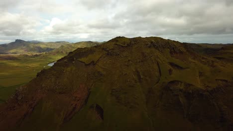 Aerial-panoramic-landscape-view-over-a-mountain-lake,-in-Iceland-grasslands