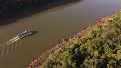 Luftaufnahme-Eines-Touristischen-Bootes,-Das-Bei-Sonnenuntergang-Auf-Dem-Iguazu-Fluss-An-Der-Argentinien-brasilianischen-Grenze-In-Südamerika-Segelt
