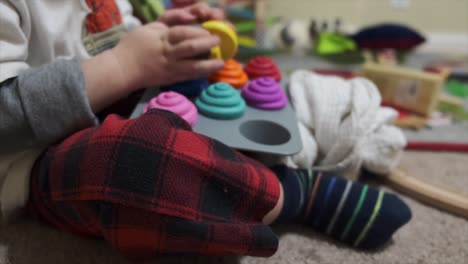 Ein-Kleines-Kind,-Das-Auf-Dem-Boden-Sitzt-Und-Mit-Plastikspielzeug-Cupcakes-Spielt