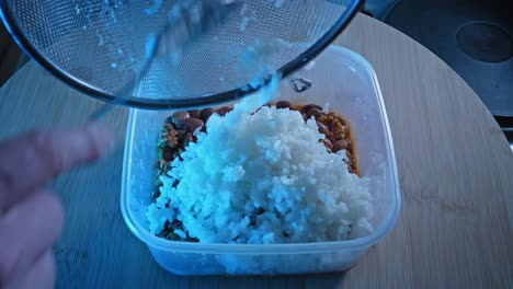 Adding-Plain-White-Rice-On-Top-Of-Cooked-Ground-Turkey-With-Beans-In-Food-Container