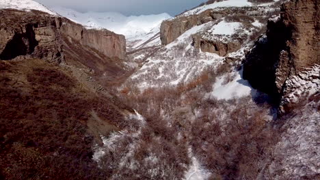 flying-through-a-rugged-wintery-canyon-with-cliffs-on-both-sides