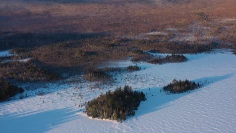 Volando-Hacia-Atrás-Desde-Un-Par-De-Islas-Cerca-De-La-Orilla-De-Un-Lago-Congelado-En-Maine