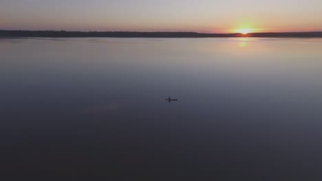 Aerial-Flying-Around-Fisherman-in-a-Boat-on-a-Lake-on-a-Calm-Summer-Evening-at-Sunset