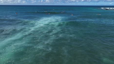 Surfers-wait-for-waves-as-whitewater-breaks-over-shallow-Hawaiian-reef,-Hookipa