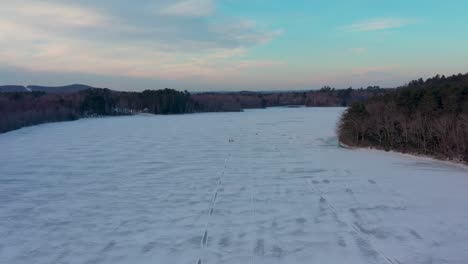 Volando-Lentamente-Hacia-Atrás-Lejos-De-Dos-Pescadores-De-Hielo-Caminando-Sobre-Un-Lago-Congelado