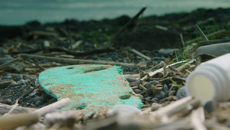 Close-up-shallow-focus-shot-of-a-flip-flop-and-other-washed-up-plastic-on-the-beach
