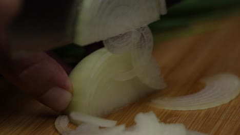 Slow-motion-close-up-macro-shot-of-slicing-onion-in-thin-pieces,-chef-preparing-vegetables-to-cook