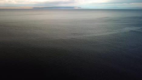 Aerial-landscape-view-of-empty-blue-ocean-water,-with-a-calm-rippled-surface