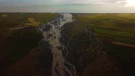 Aerial-landscape-view-of-a-glacier-river-flowing-in-a-valley,-with-many-branches,-on-dark-sand,-Iceland