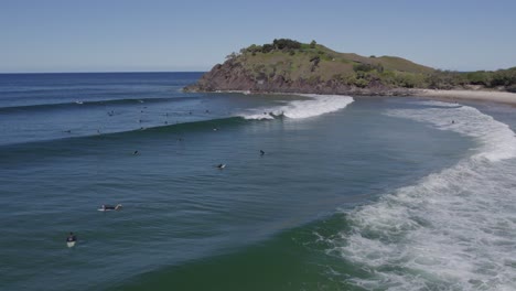People-Surfing-At-Cabarita-Beach-With-Norries-Headland-In-NSW,-Australia---aerial-drone-shot