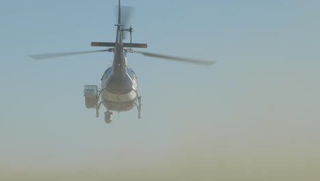 A-helicopter-taking-flight-in-the-desert-with-cars-driving-past-and-dust-cloud