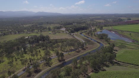 Channel-Water-Flowing-Through-Fields-With-Green-Trees-In-Rural-Town-Of-Arriga-Near-Walkamin-In-North-Queensland,-Australia