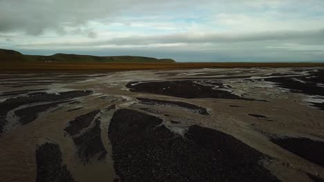 Vista-Aérea-Del-Paisaje-De-Un-Río-Glaciar-Con-Muchas-Ramas-Que-Fluyen-En-Un-Valle,-Sobre-Arena-Oscura,-En-Islandia