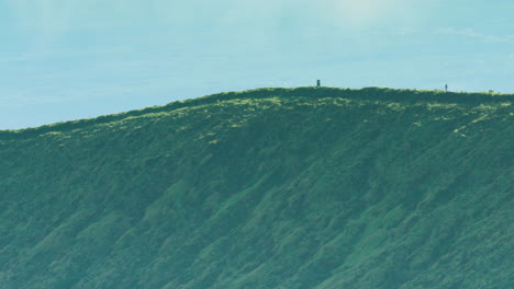 Dramatic-long-lens-shot-of-two-joggers-making-their-way-along-the-rim-of-the-Caldeira-volcano,-The-Azores