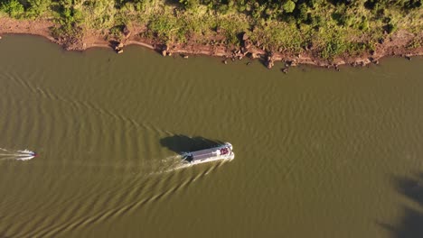 Aerial-top-down-shot-of-tourist-boat-and-speedboat-sailing-on-Iguazu-River-during-sunny-day---Visiting-Argentina-and-Brazil-Country