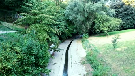 Aerial-view-of-small-canal-water-at-Petrusse-Valley-nature-with-athlete-runner