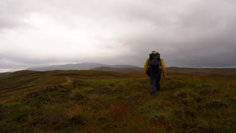 Hiking-over-Scottish-Moorland-through-heather-towards-Hills-on-a-Moody-Day