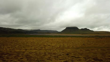 Vista-Aérea-Del-Paisaje-De-Un-Río-Glaciar-Que-Fluye-En-Un-Valle,-Sobre-Arena-Oscura,-En-Islandia