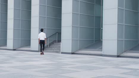 Slow-motion-shot-of-Young-Businessman-walking-into-Financial-building-staircase,-Modern-facade