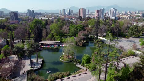 Aerial-view-of-the-lagoon-of-Quinta-Normal-park,-a-place-of-recreation-for-the-people-of-Santiago,-Santiago-architecture-in-the-background,-Chile