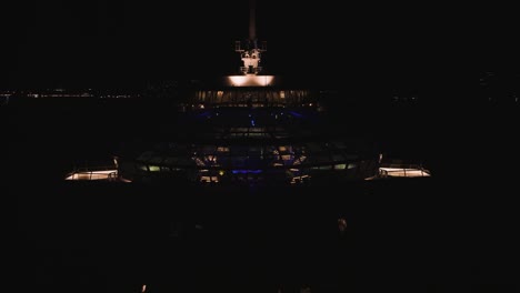 Aerial-drone-shot-over-a-pool-and-gym-inside-a-large-Quantum-of-the-seas-cruise-ship-off-the-Lahaina-shores,-Hawaii,-USA-at-dark-night