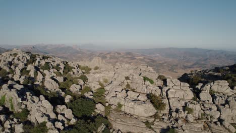 Aerial-drone-backward-moving-shot-over-impressive-rocky-mountain-tops-in-Torcal-de-Antequera,-Karstik-rocks,-Spain-at-dusk