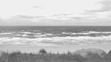 Waving-sea-with-the-view-over-a-dune-at-a-beach-in-black-and-white