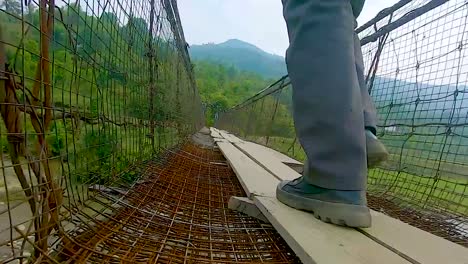 Hombre-Caminando-En-Un-Puente-Colgante-De-Hierro-Antiguo-Desde-Un-ángulo-Bajo-Se-Toma-Un-Video-En-Nongjrong-Meghalaya-India