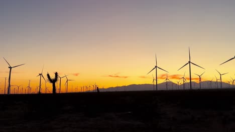 Silhouette-Wind-Turbine-Farm-With-Golden-Orange-Sunset-Skies