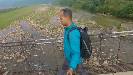 young-traveler-man-walking-on-iron-suspension-bridge-at-morning