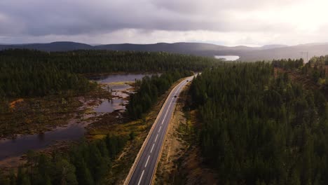 Cars-driving-int-the-sunset-on-forest-road-in-Inari-Finland,-cinematic-aerial-view