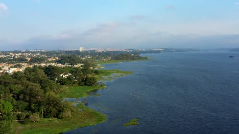 Beautiful-rotating-aerial-drone-shot-of-the-man-made-Guarapiranga-Reservoir-in-the-south-part-of-São-Paulo,-Brazil-with-beaches,-marinas,-natural-green-ecosystems,-and-wildlife-on-a-fall-evening
