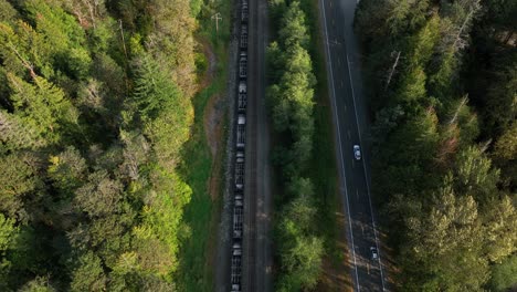 Top-down-aerial-view-of-a-train-racing-cars-on-the-highway