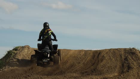 A-static-shot-of-few-riders-driving-quad-bikes-over-a-sandy-desert-hill-in-the-morning-time-from-rear