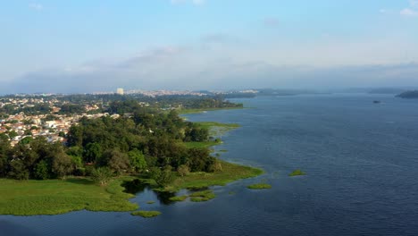 Beautiful-dolly-in-aerial-drone-shot-of-the-man-made-Guarapiranga-Reservoir-in-the-south-part-of-São-Paulo,-Brazil-with-beaches,-marinas,-natural-green-ecosystems,-and-wildlife-on-a-fall-evening