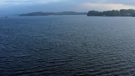 Dolly-out-tilting-up-aerial-drone-shot-of-the-stunning-man-made-Guarapiranga-Reservoir-in-the-south-of-São-Paulo,-Brazil-with-calm-waters,-beaches,-marinas,-and-wildlife-on-an-overcast-fall-evening
