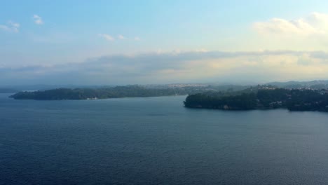 Beautiful-ascending-aerial-drone-shot-of-the-stunning-man-made-Guarapiranga-Reservoir-in-the-south-part-of-São-Paulo,-Brazil-with-beaches,-marinas,-and-wildlife-on-a-fall-foggy-evening