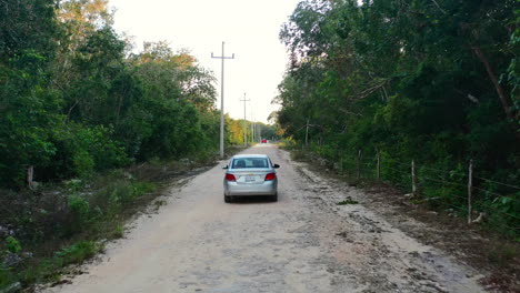 aerial-tracking-shot-of-car-driving-on-road-in-Coba-Quintana-Roo-Mexico-at-sunset