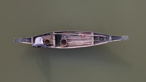 Lonely-man-fishing-in-traditional-wooden-fishing-boat-in-Asia,-top-down-view