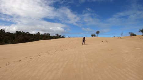 A-young-boy-runs-off-into-the-distance-on-large-coastal-dunes