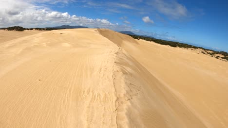 A-point-of-view-shot-of-walking-along-a-sand-dune-ridge-in-an-epic-landscape