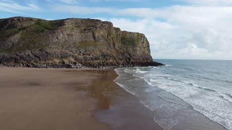 Aerial-Drone-Shot-on-Mewslade-Bay-in-Gower-Peninsula-with-Dramatic-Coastal-Cliff-and-Rolling-Sea-Waves-and-Blue-Sky-4K