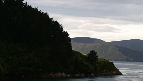 Exploring-the-fiords-of-Queen-Charlotte-sound,-New-Zealand-in-soft-evening-sunlight
