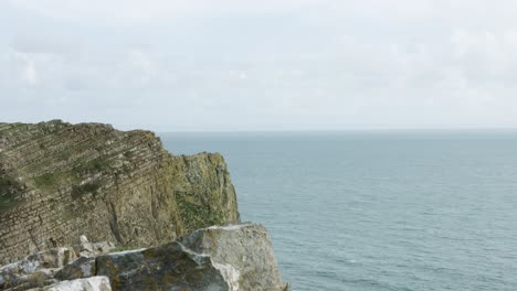 Dramatische-Küstenklippe-Mit-Sichtbaren-Felsschichten-Und-Meeresoffenbarung-Als-Kameraschwenks-Am-Strand-Von-Mewslade-Auf-Der-Halbinsel-Gower,-Wales,-Großbritannien-4k