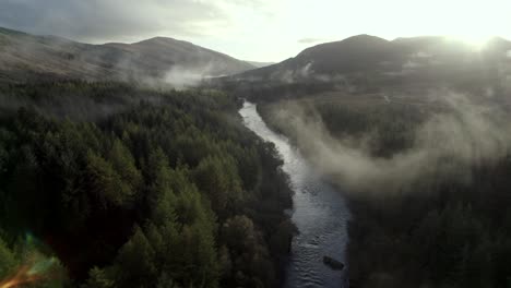 Drone-footage-rises-above-a-slow-moving-river-and-a-dark-forest-of-conifer-trees