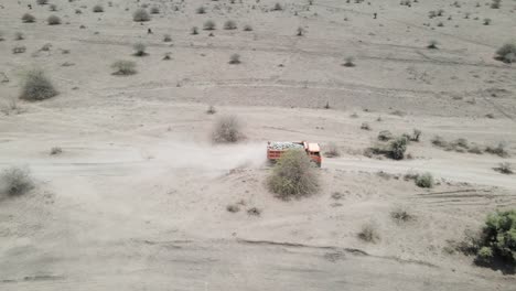 Aerial-View-of-truck-driving-on-rough-dirt-road-transporting-rocks