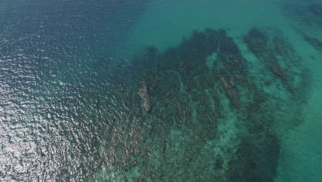 Arrecifes-De-Roca-Bajo-Un-Mar-Turquesa-Poco-Profundo-Con-Reflejo-De-La-Luz-Del-Sol-En-La-Superficie