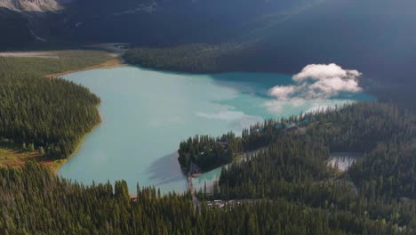 Aerial-rising-over-Lake-Louise-between-woods-and-Canadian-Rockies-at-Fairmont-Hot-Springs,-Banff-National-Park,-Alberta,-Canada